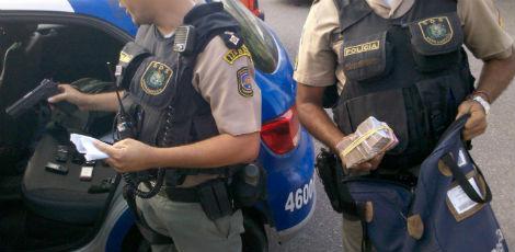 Policiais mostram o que recuperaram com um dos assaltantes: malote com dinheiro, armas e celulares 
 / Foto: Davi Barboza / Especial para o JC