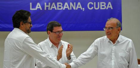 Chefe da delegação colombiana para conversas para a paz, Humberto de la Calle (direita) e comandante das FARC, Commander Ivan Marquez (esquerda) apertam as mão após assinatura de acordo de paz / Foto: YAMIL LAGE / AFP