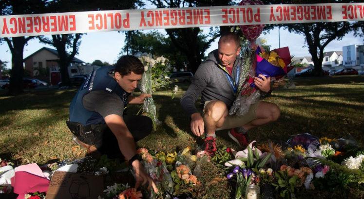 Policiais levam flores para local do crime / Foto: Marty MELVILLE / AFP